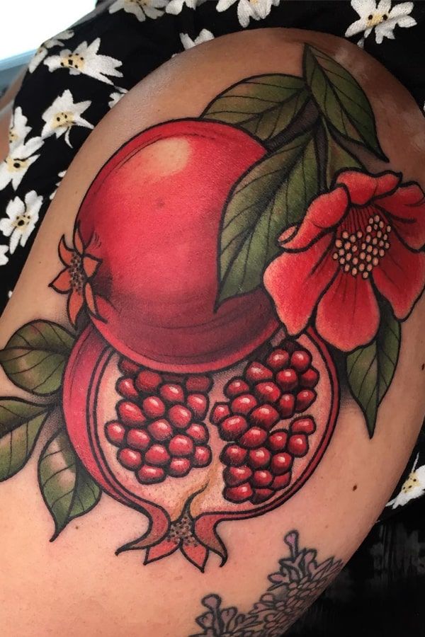 a woman with a tattoo on her arm has a pomegranate and flowers