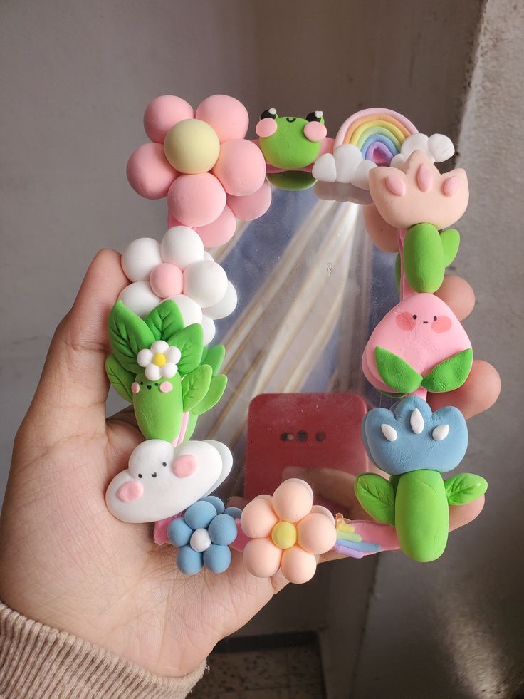 a person holding up a small mirror with flowers and animals on it's sides