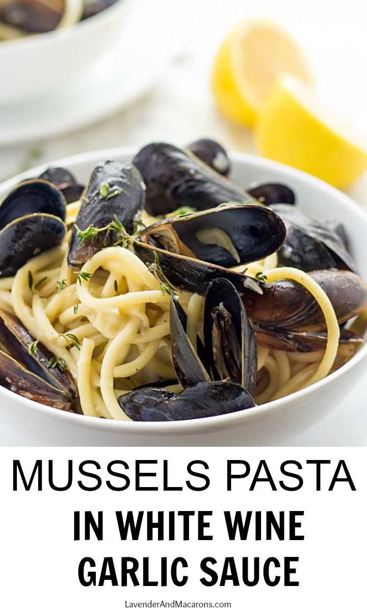 mussels pasta in a white wine sauce with lemon wedges on the side