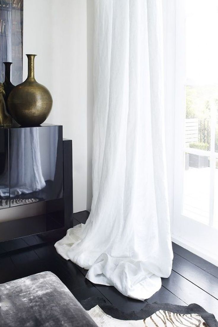 a living room with white curtains and black furniture