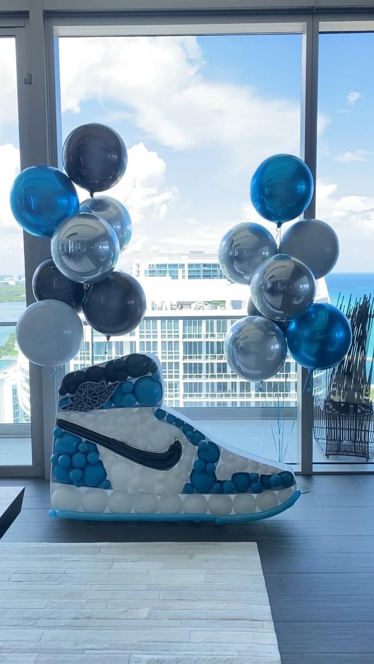 a pair of sneakers with balloons attached to them in front of a window overlooking the ocean