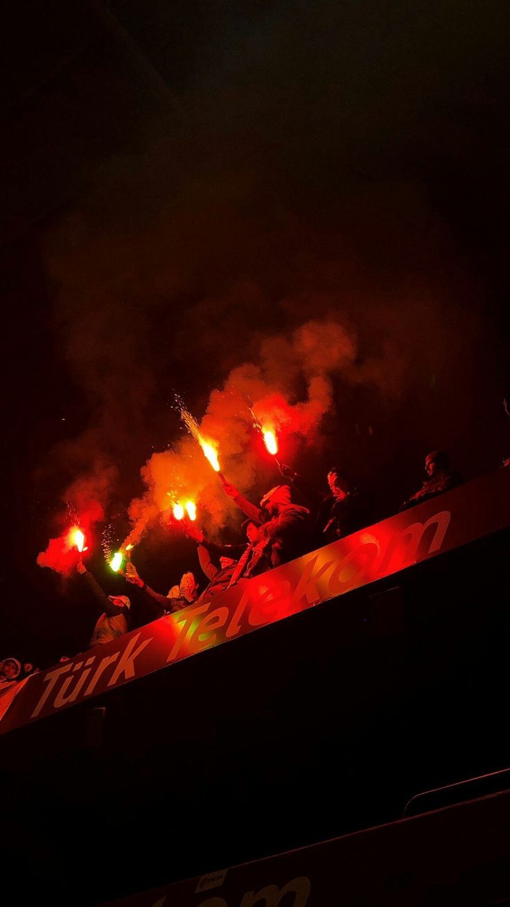 fireworks are lit up in the night sky above a stadium's bleachers