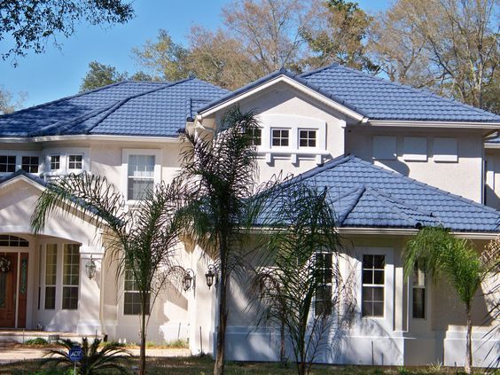 a white house with blue roofing and palm trees