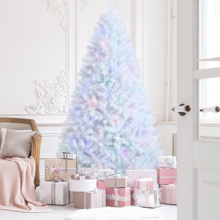 a white christmas tree with pastel colors and presents under it in front of a window