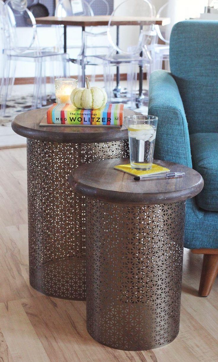 two side tables with books and drinks on them in a living room area next to a blue chair