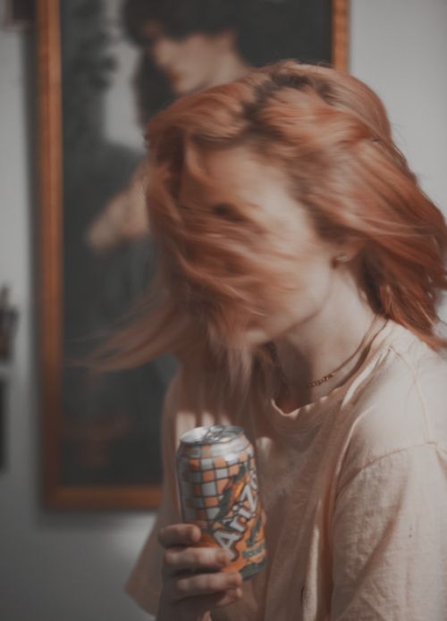 a woman with red hair is holding a can