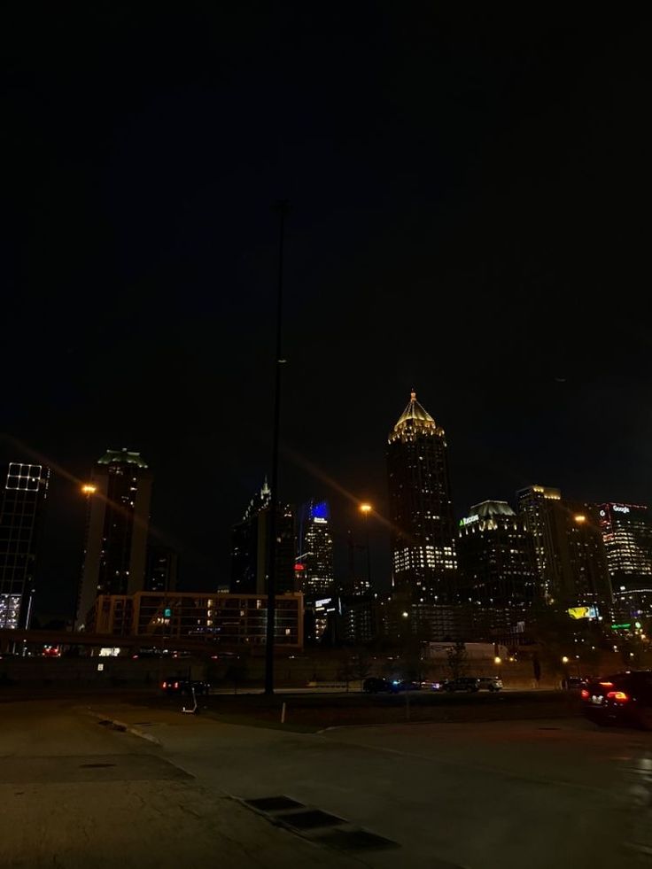 the city skyline is lit up at night with bright lights and skyscrapers in the background