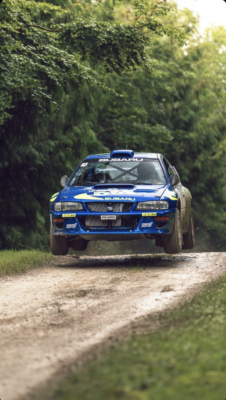 a blue car driving down a dirt road