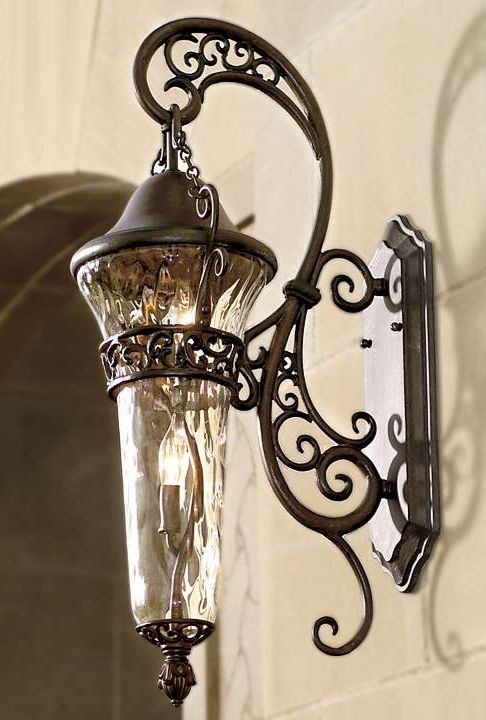 an old fashioned light fixture hanging from the side of a wall in a building or home