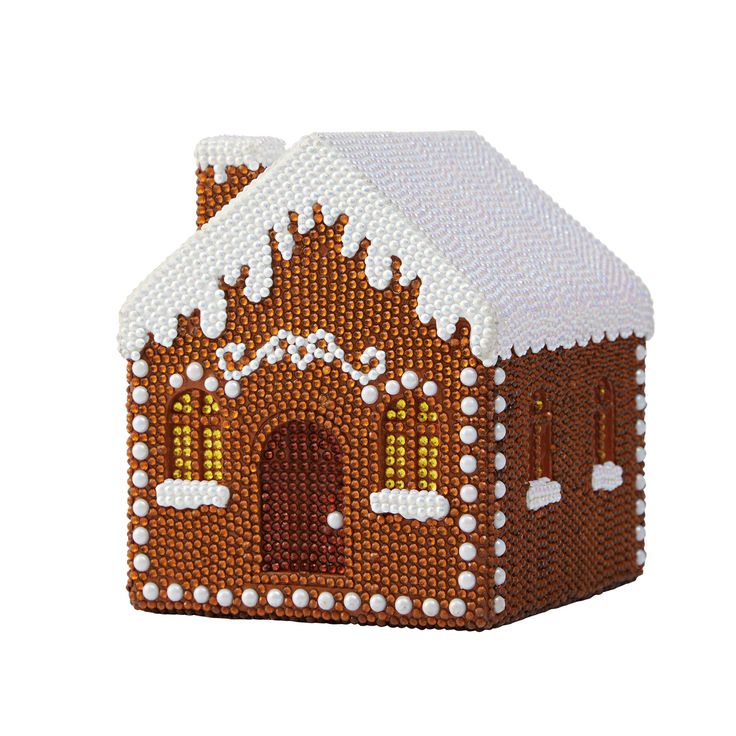 a small brown and white house made out of beads with snow on the roof, sitting in front of a white background