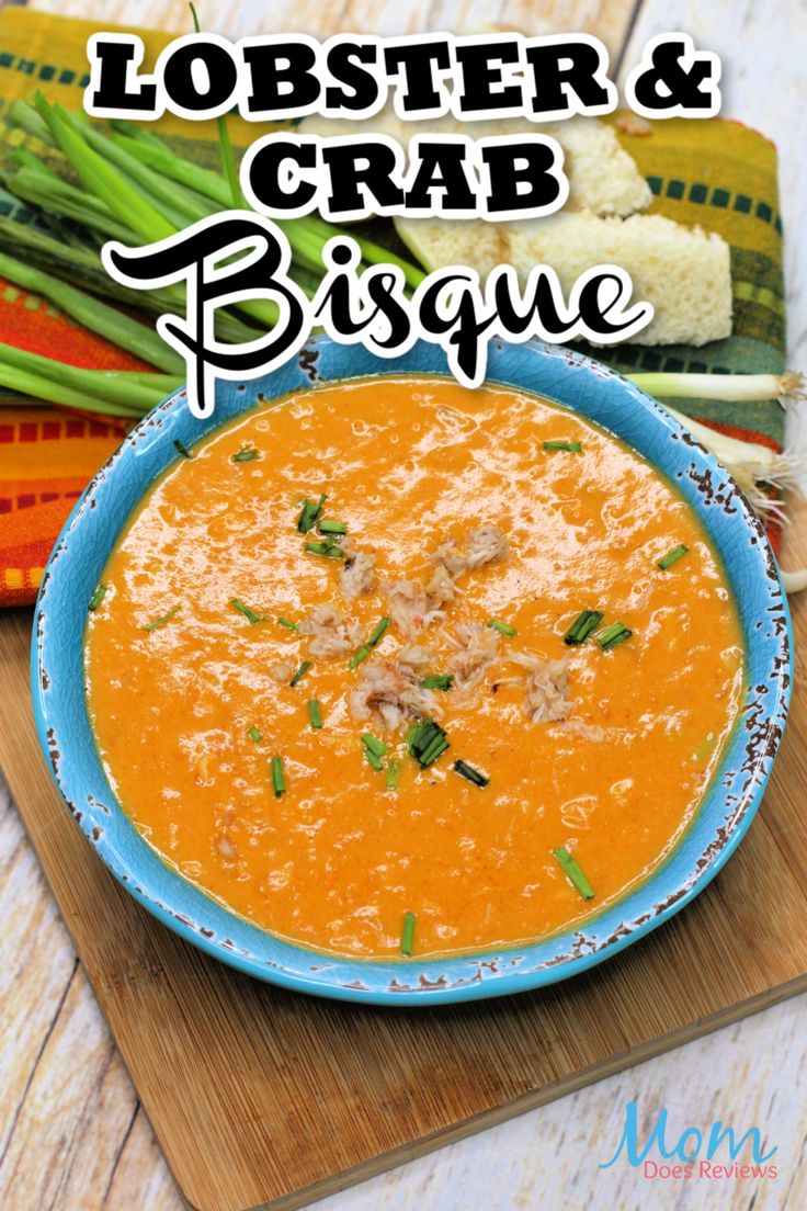 lobster and crab bisque in a blue bowl on a cutting board with green onions