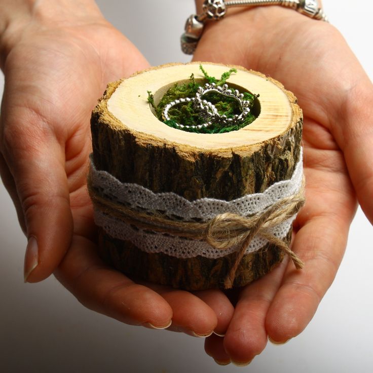 two hands holding a piece of wood with lace on it and a wedding ring in the center