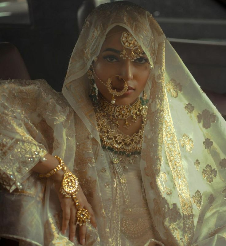 a woman in a car wearing gold jewelry and a veil with her hands on her hips