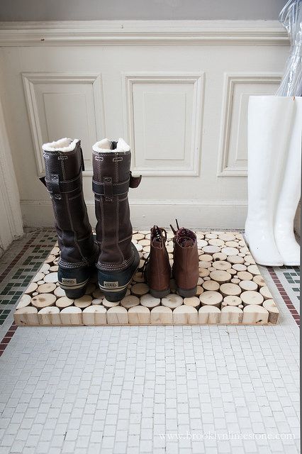 two pairs of boots sitting on top of a mat in the middle of a room