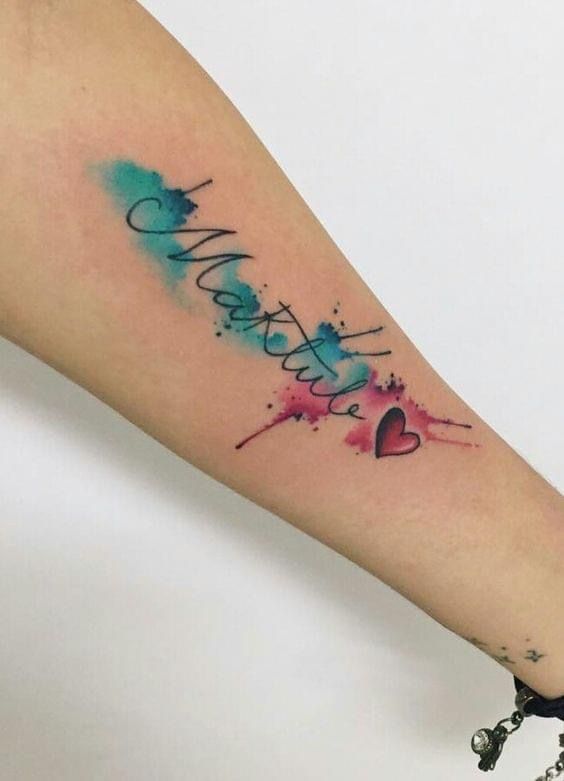 a woman's arm with a watercolor tattoo that reads, love is in the air