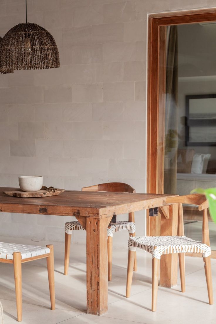 a wooden table with two chairs and a bowl sitting on top of it next to a window