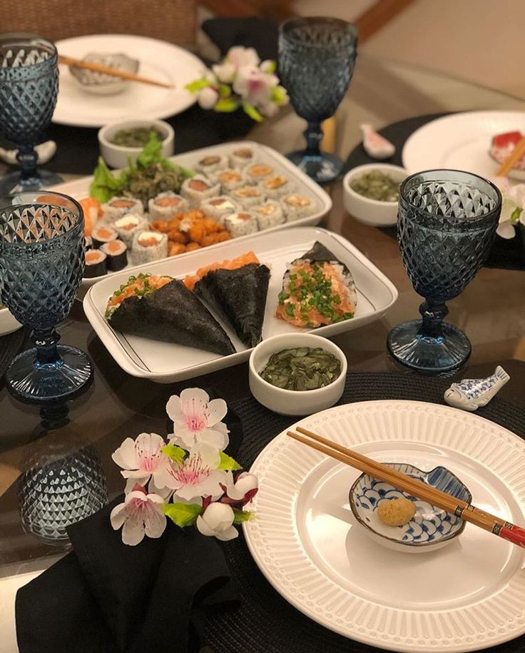 the table is set with plates, bowls and dishes for sushi or other food