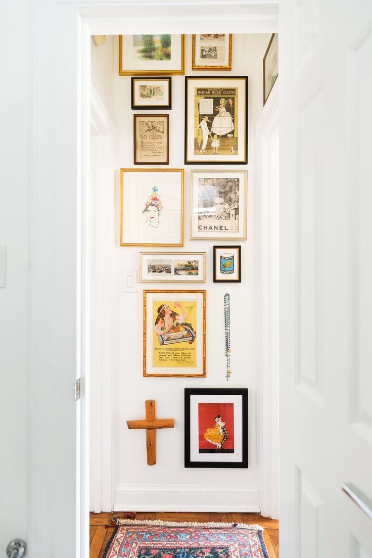 a hallway with pictures on the wall and a rug in front of an open door