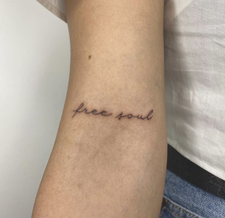 a woman's arm with the word free soul written on it, in cursive font