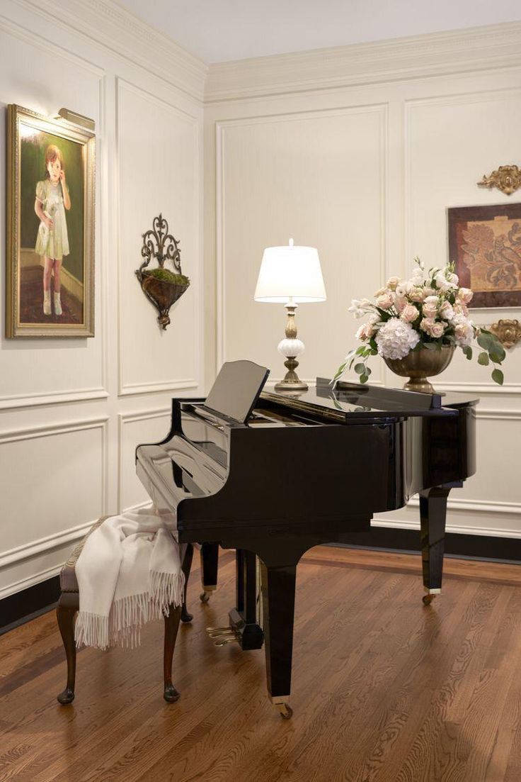 a grand piano sits in the center of a room with white walls and wood floors