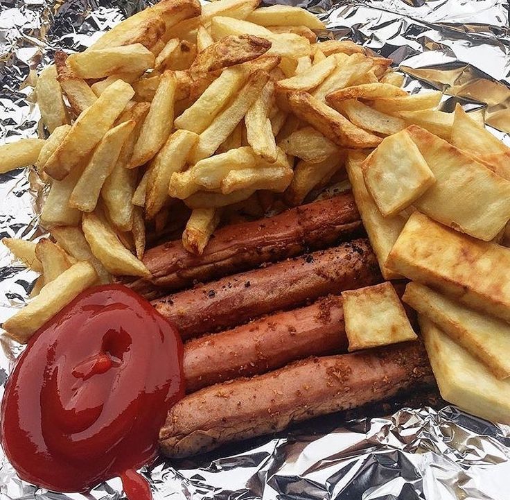 a pile of food sitting on top of foil covered in ketchup and french fries