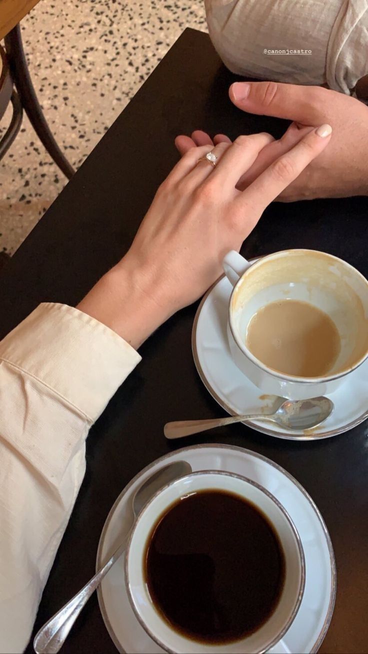 two people sitting at a table with cups of coffee