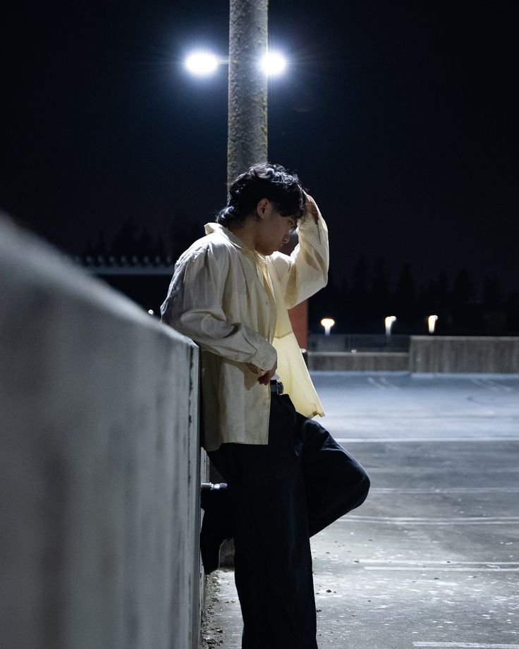 a man leaning against a wall at night