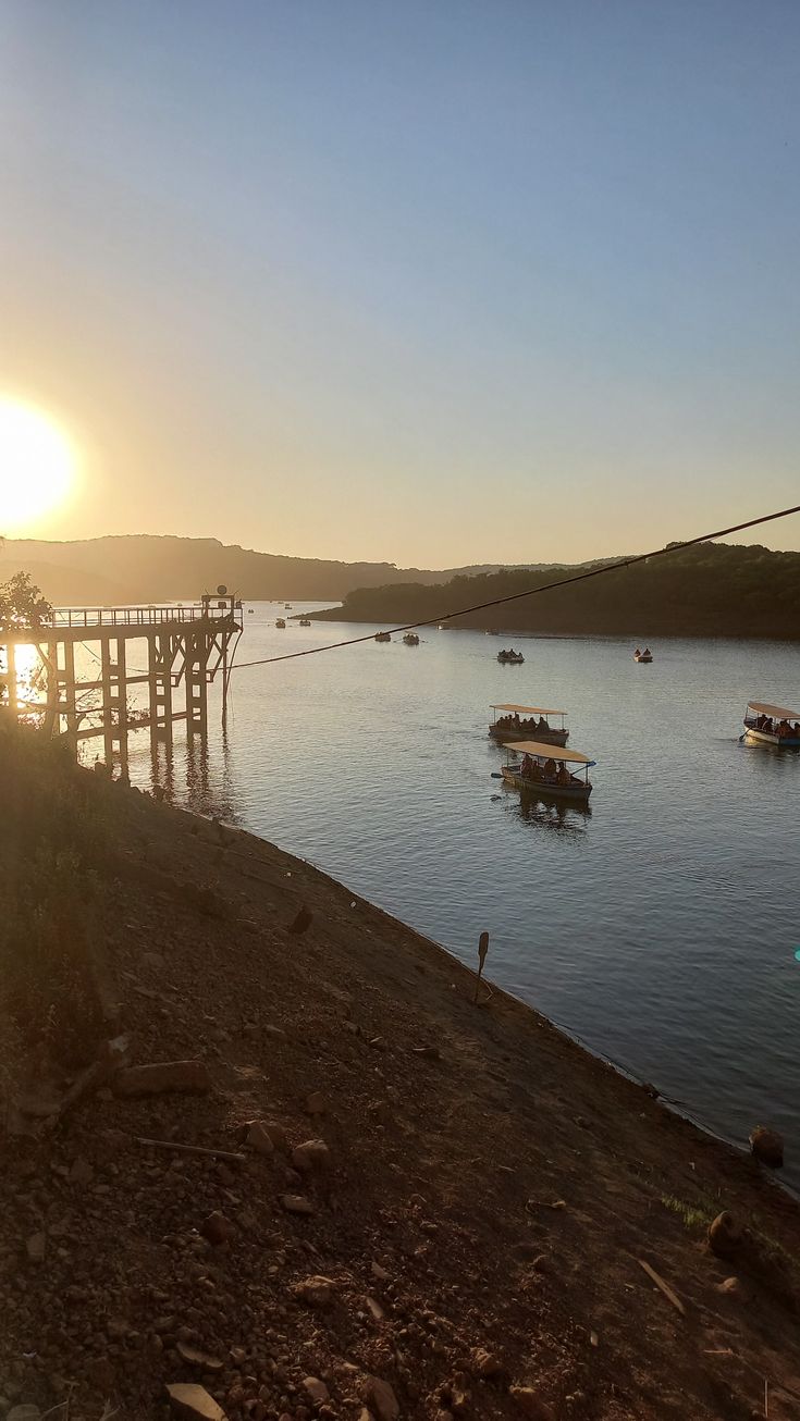 several boats floating in the water at sunset