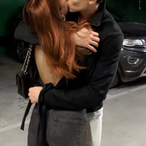 a man and woman kissing in front of a car