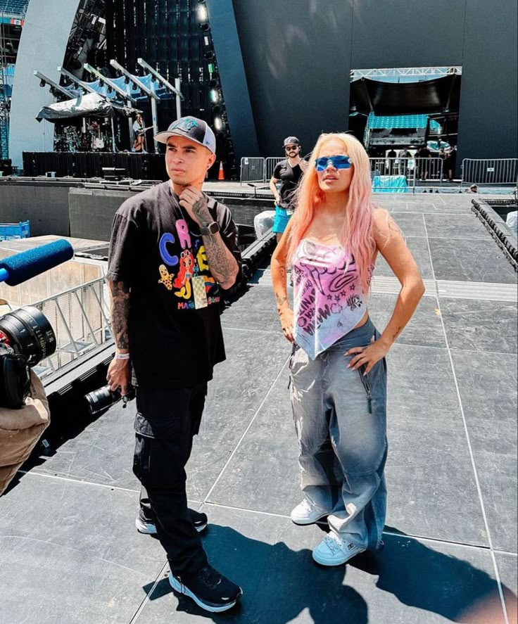 a man standing next to a woman in front of a stage with people on it