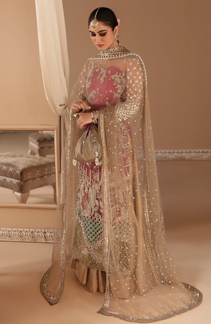 a woman in a pink and gold outfit standing next to a white bed with curtains