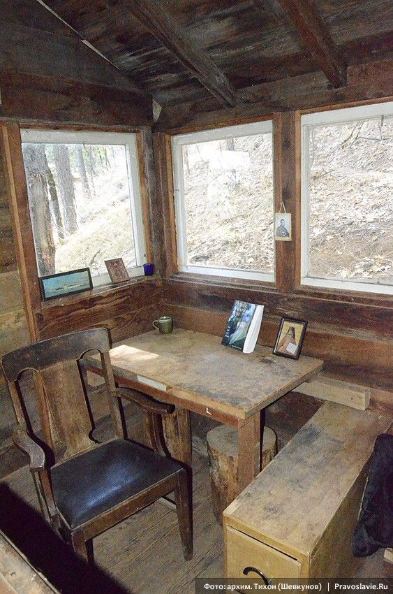 a table and two chairs in a room with wood paneling on the walls, along with three windows