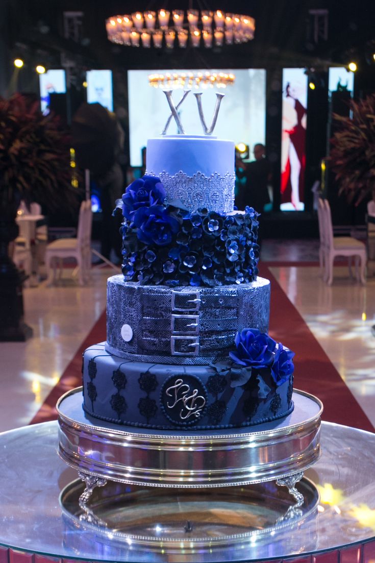 a three tiered cake with blue frosting and flowers on it's side