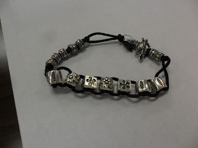 a black cord bracelet with silver beads and letters that spell out the word i love you