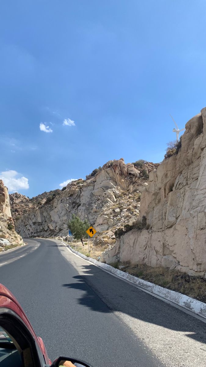 a car driving down the road next to a mountain