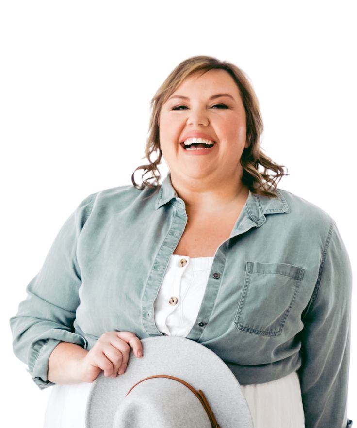 a woman in a blue shirt and white skirt holding a hat smiling at the camera