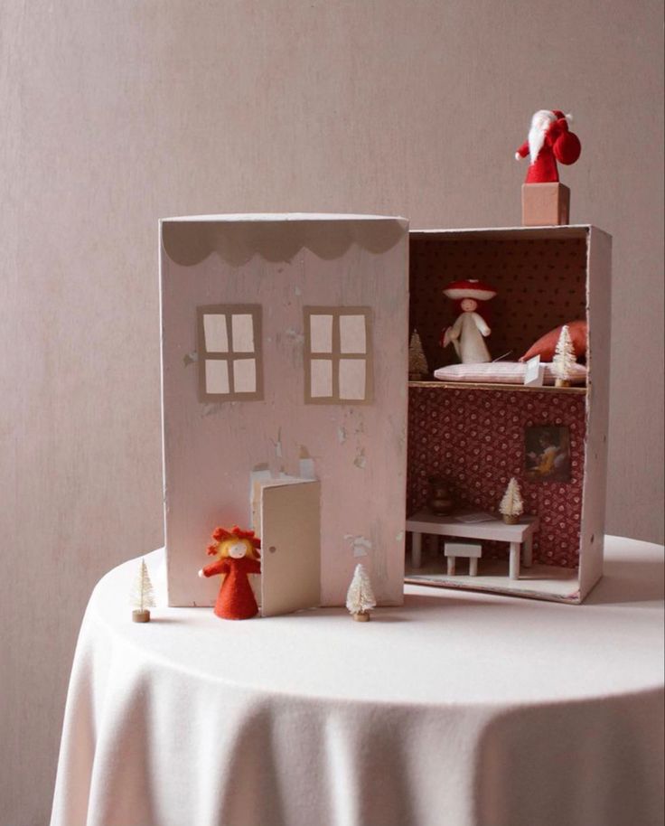 a doll house sitting on top of a table next to a white tablecloth covered table