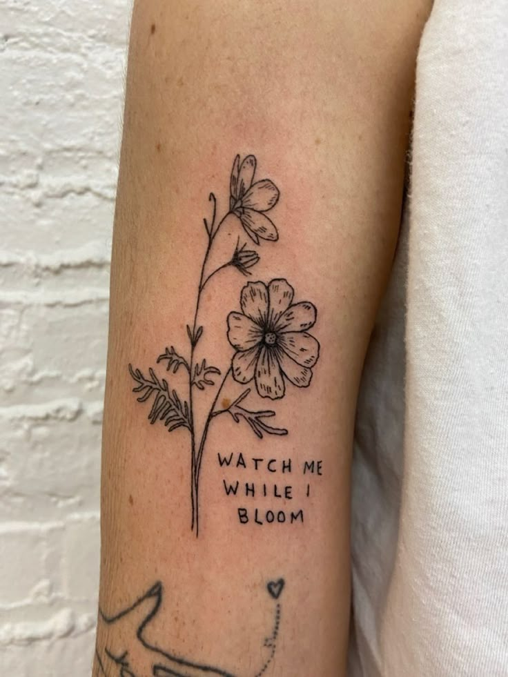 a woman with a tattoo on her arm that says watch me, while i bloom