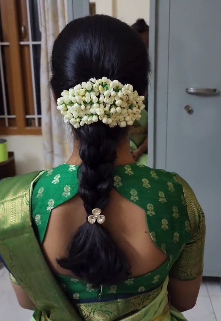 a woman wearing a green sari with flowers in her hair