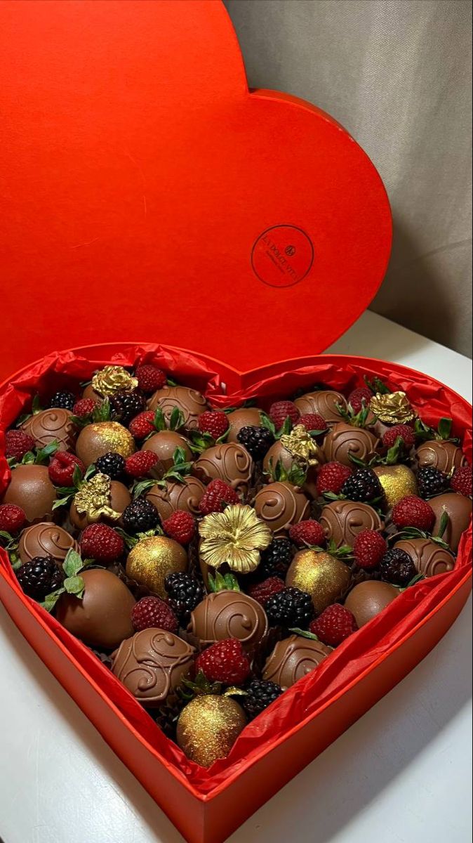 a heart shaped box filled with chocolate covered strawberries