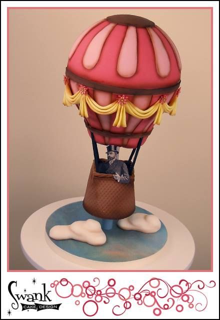 a cake with a hot air balloon on it's top and clouds around it