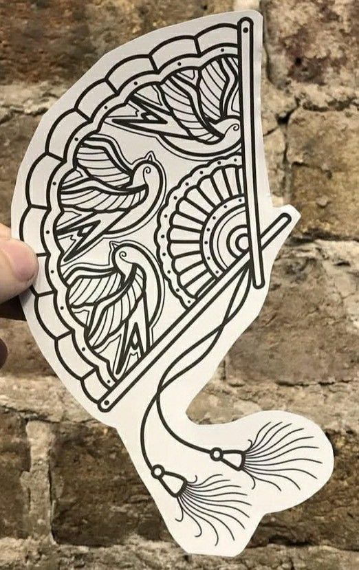 a hand holding up a sticker with an image of a fish on it's side