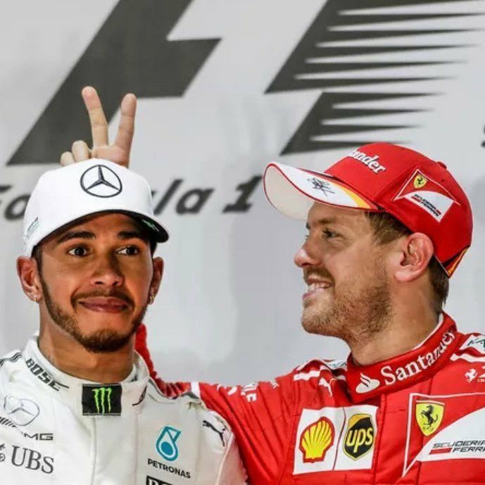 two men standing next to each other on top of a race track with one giving the peace sign