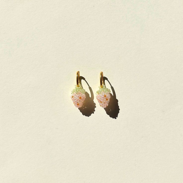 two pairs of earrings sitting on top of a white surface