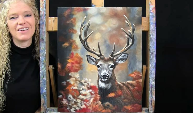 a woman standing next to an easel with a painting of a deer on it