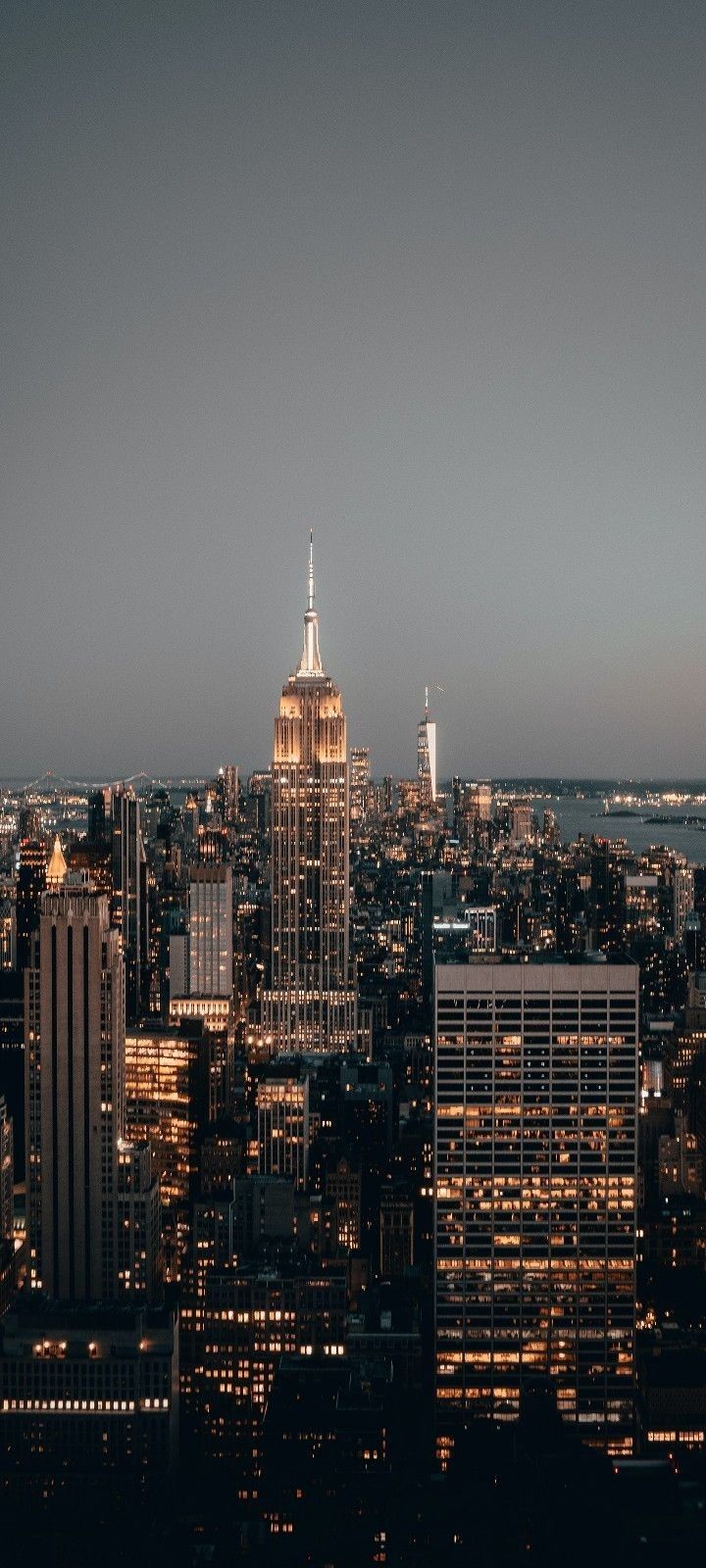 the city skyline is lit up at night, with skyscrapers in the foreground