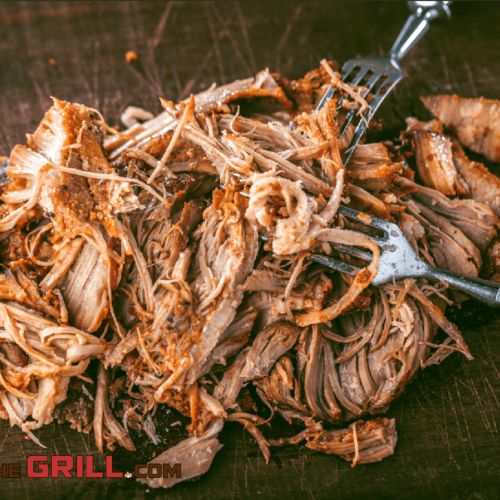 a pile of shredded meat sitting on top of a cutting board next to a fork