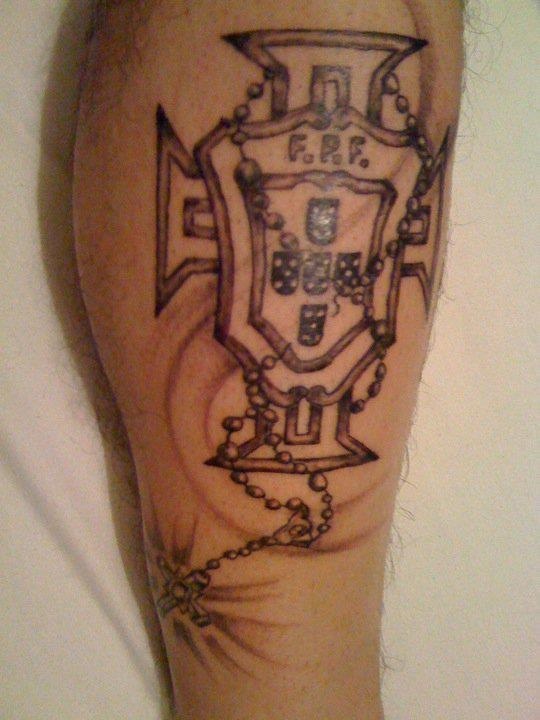 a man's leg with a tattoo on it that has a shield and chain attached to it