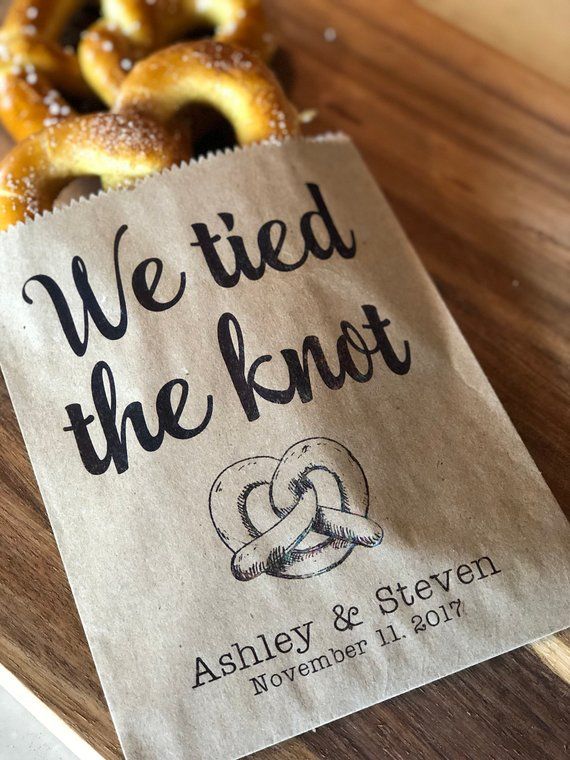 some pretzels sitting on top of a wooden table next to a bag with the words we tied the knot