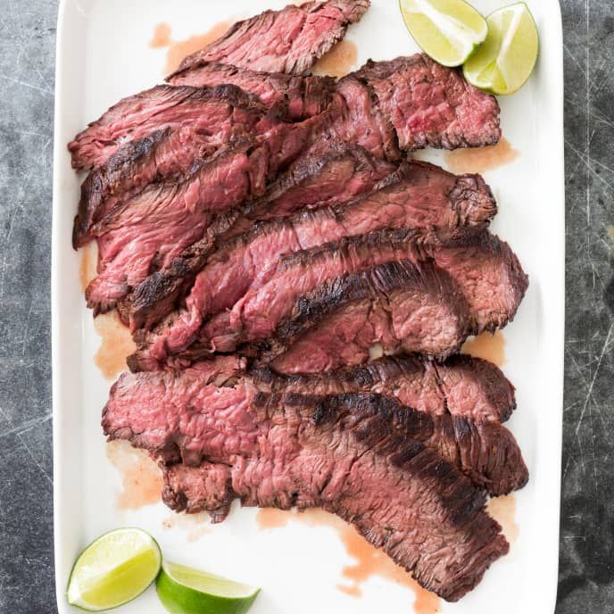 sliced steak on a plate with lime wedges